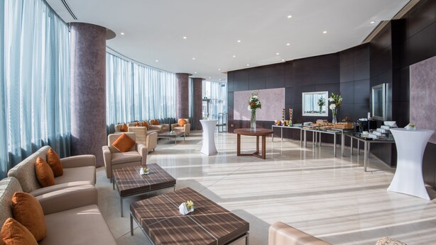 A spacious lobby with sofas, tables, and a reception area.