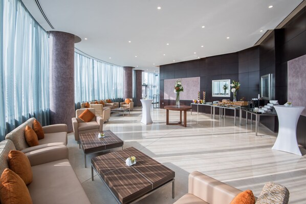 A spacious lobby with sofas, tables, and a reception area.