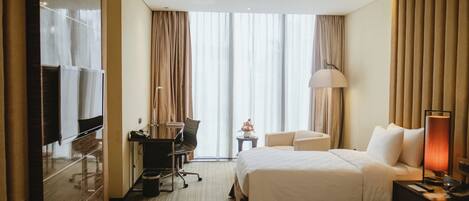 A hotel room with two beds, a desk with a chair, a television, and a lamp.