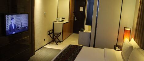 A hotel room with a bed, a TV, a desk, and a bathroom.
