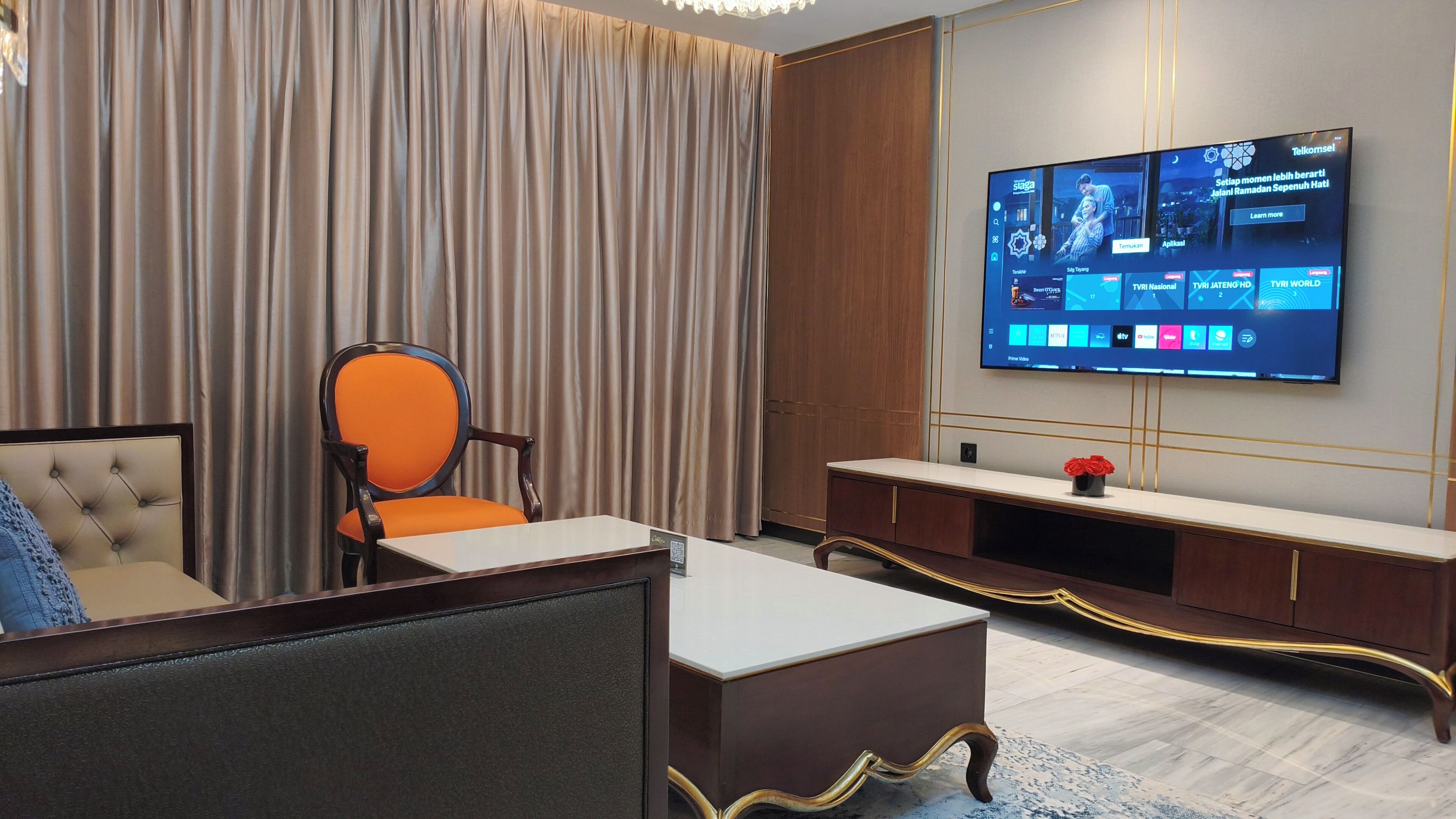 Een moderne woonkamer met een televisie, een bank, een fauteuil en een salontafel.
