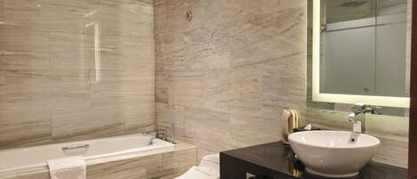 A modern bathroom with a bathtub, toilet, and sink, all in a neutral color palette.