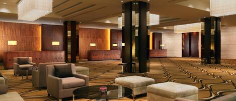 A spacious lobby with a patterned carpet, multiple seating areas, and modern lighting fixtures.