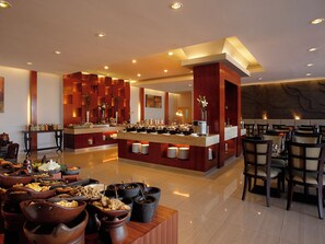 A modern dining area with a central buffet, multiple seating arrangements, and a polished floor. - Hotel Santika Jemursari Surabaya (Surabaya)