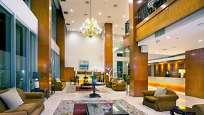 A hotel lobby with a reception desk, seating area, and a chandelier. - Hotel Santika Jemursari Surabaya (Surabaya)