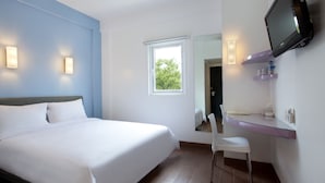 Habitación de hotel con cama, escritorio, silla, televisión y ventana.