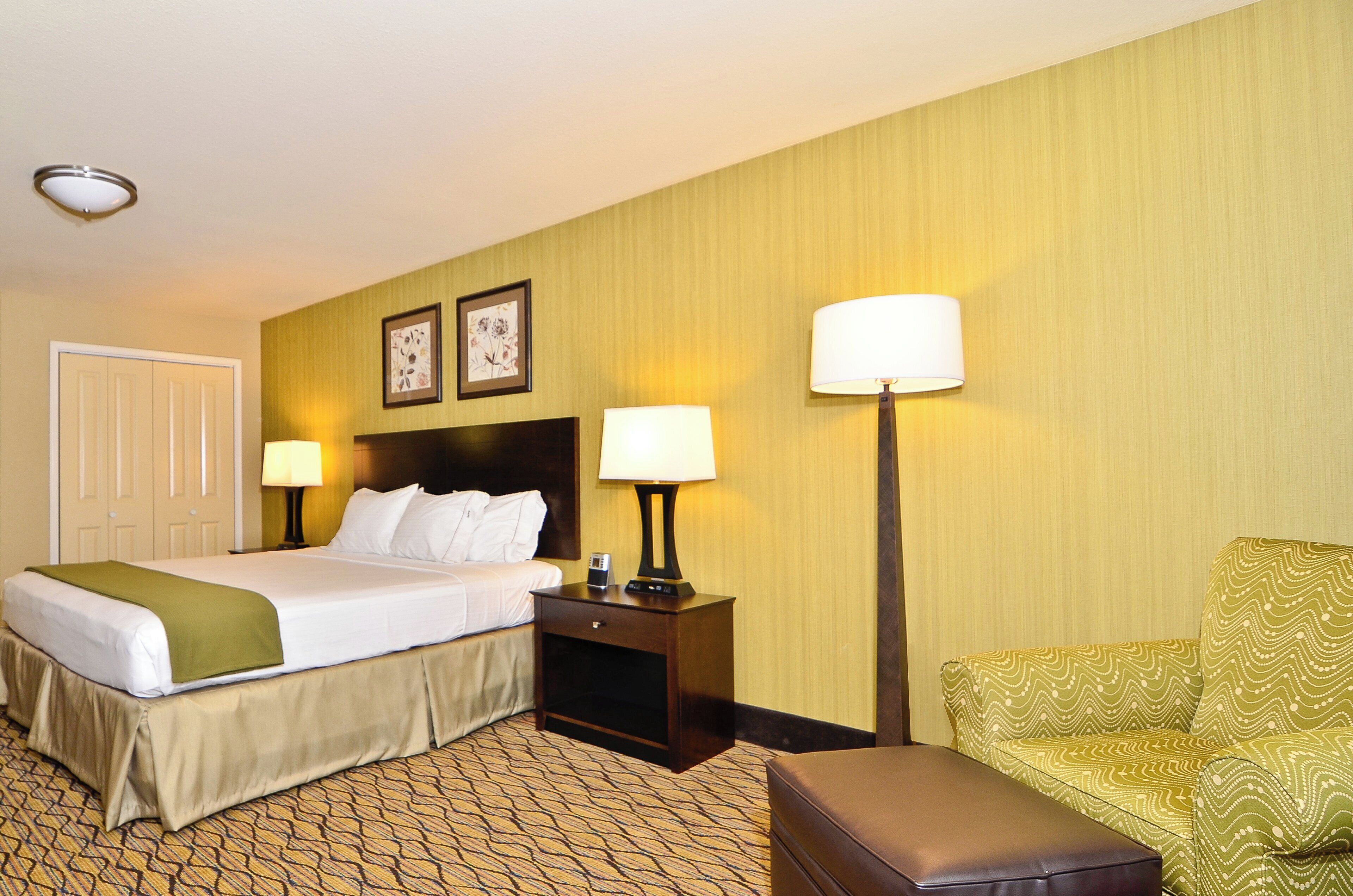 Een hotelkamer met een bed, bedlampjes, een nachtkastje, een stoel en een deur.