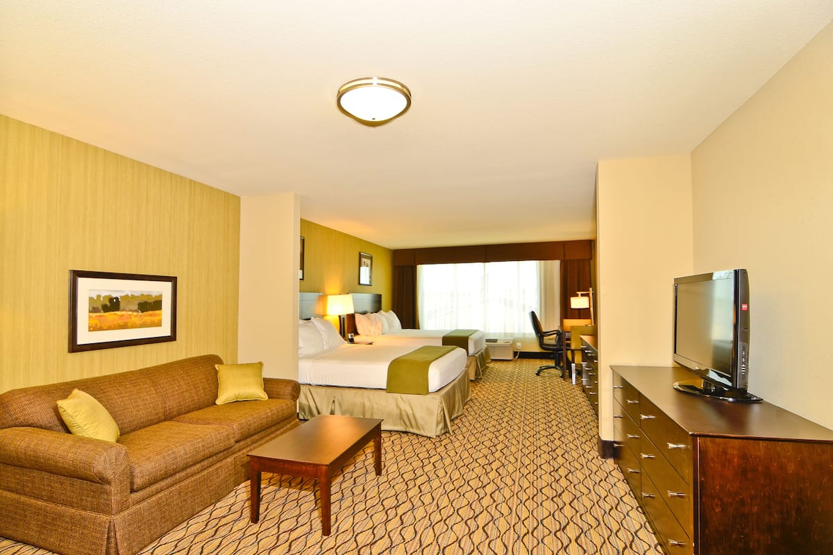 A hotel room with a bed, a sofa, a TV, and a desk.