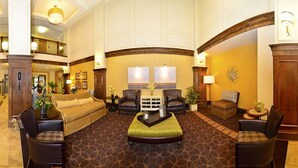 A spacious lobby with a high ceiling, a central seating area with a sofa and chairs, and a patterned carpet. - Holiday Inn Express and Suites Williston by IHG (Williston)