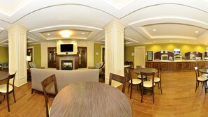 A spacious hotel lobby with a fireplace, seating area, and a counter with amenities. - Holiday Inn Express and Suites Williston by IHG (Williston)