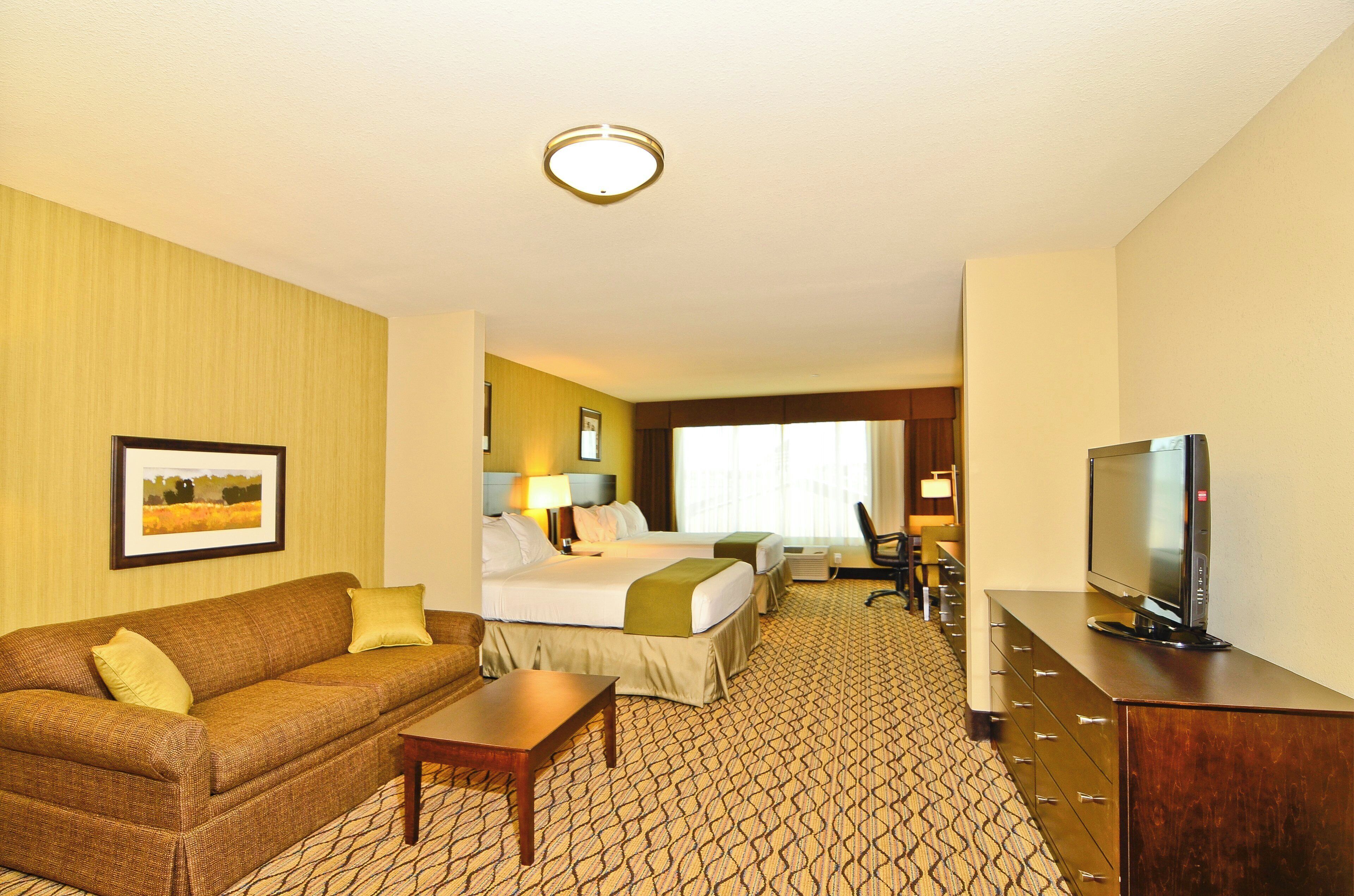 A hotel room with a bed, a sofa, a television, and a desk.