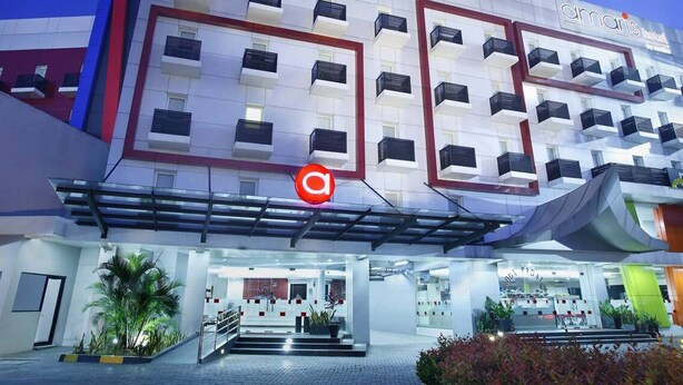 A modern hotel with a prominent 'Amaris Hotel' sign, multiple balconies, and a well-lit entrance area with steps and potted plants. - Amaris Hotel - Bandara Soekarno Hatta (Tangerang)