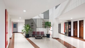 A modern hotel lobby with a central seating area, potted plants, and a staircase. - Amaris Hotel - Bandara Soekarno Hatta (Tangerang)