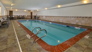 An indoor swimming pool with a tiled floor, a pool ladder, and a seating area with chairs. - Hampton Inn Ottumwa (Ottumwa)