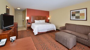 A hotel room with a bed, a television, a desk, a couch, and a painting on the wall. - Hampton Inn Ottumwa (Ottumwa)