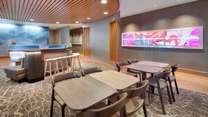 Een moderne hotellobby met een receptiebalie, een bar en zithoekjes.