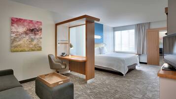 Ein modernes Hotelzimmer mit Bett, Schreibtisch mit Stuhl, Fernseher und großem Fenster.