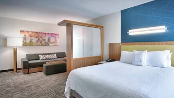 Una habitación de hotel con cama, sofá, escritorio y un ventanal grande.