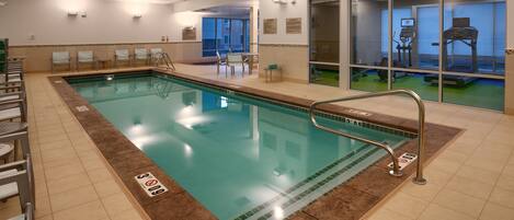 An indoor swimming pool with a 3ft depth marker, lounge chairs, and exercise equipment.