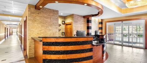 A reception area with a curved wooden counter, a stone wall, and a door leading to the outside.