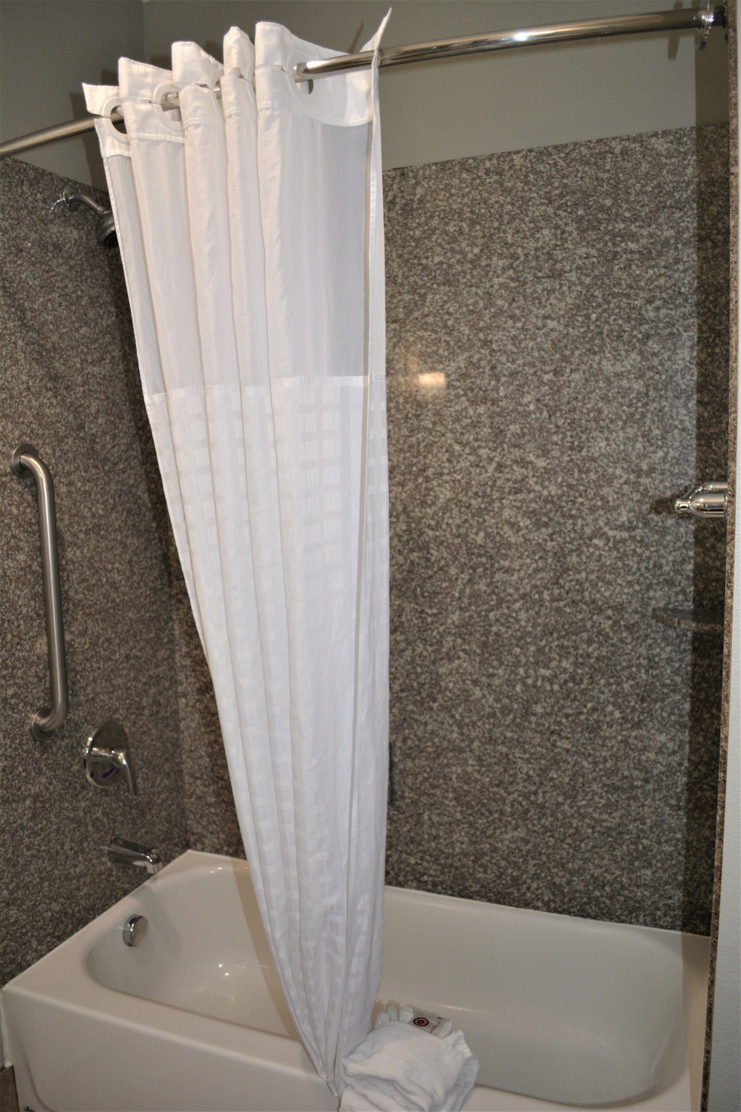 A bathroom with a shower curtain, a grab bar, and a bathtub.