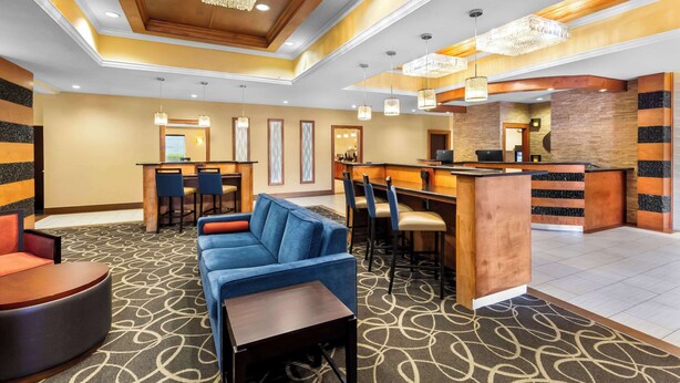 A hotel lobby with a blue sofa, a round table, a reception desk, and a bar area. - Comfort Suites at Katy Mills (Katy)