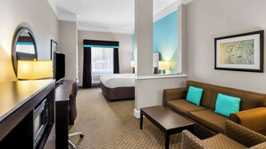 A hotel room with a bed, a desk with a computer, a sofa, and a window with curtains. - Comfort Suites at Katy Mills (Katy)