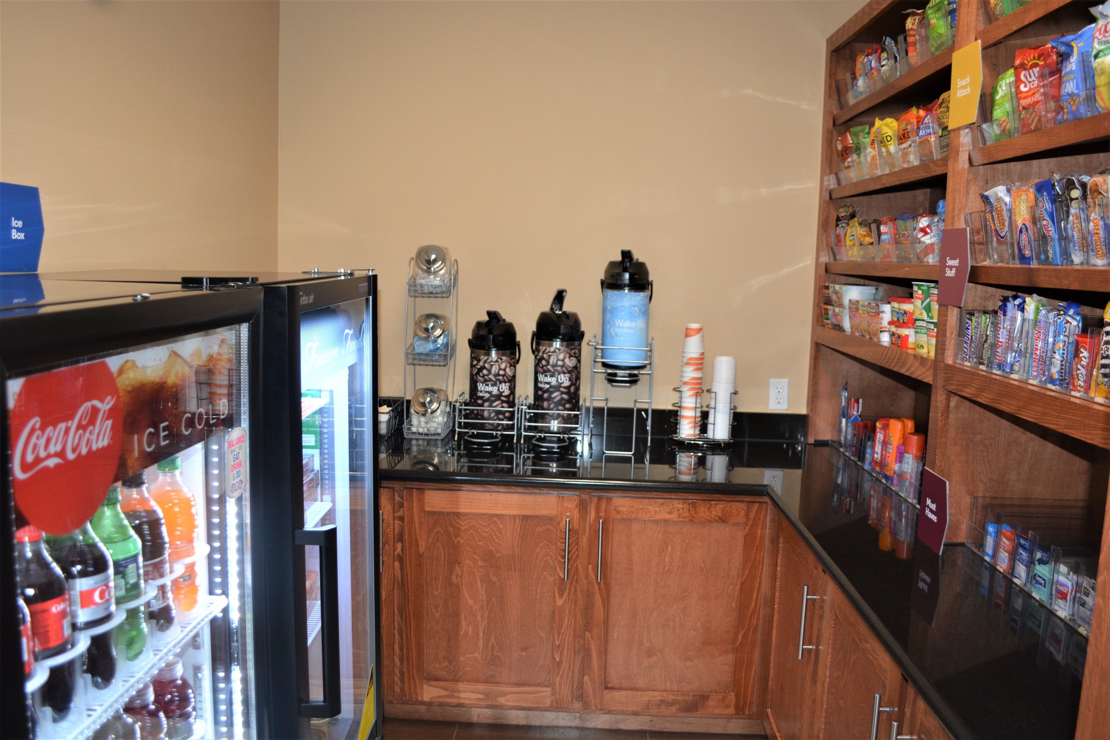 A beverage dispenser with Coca-Cola and other sodas, a coffee machine, and shelves stocked with snacks and beverages.