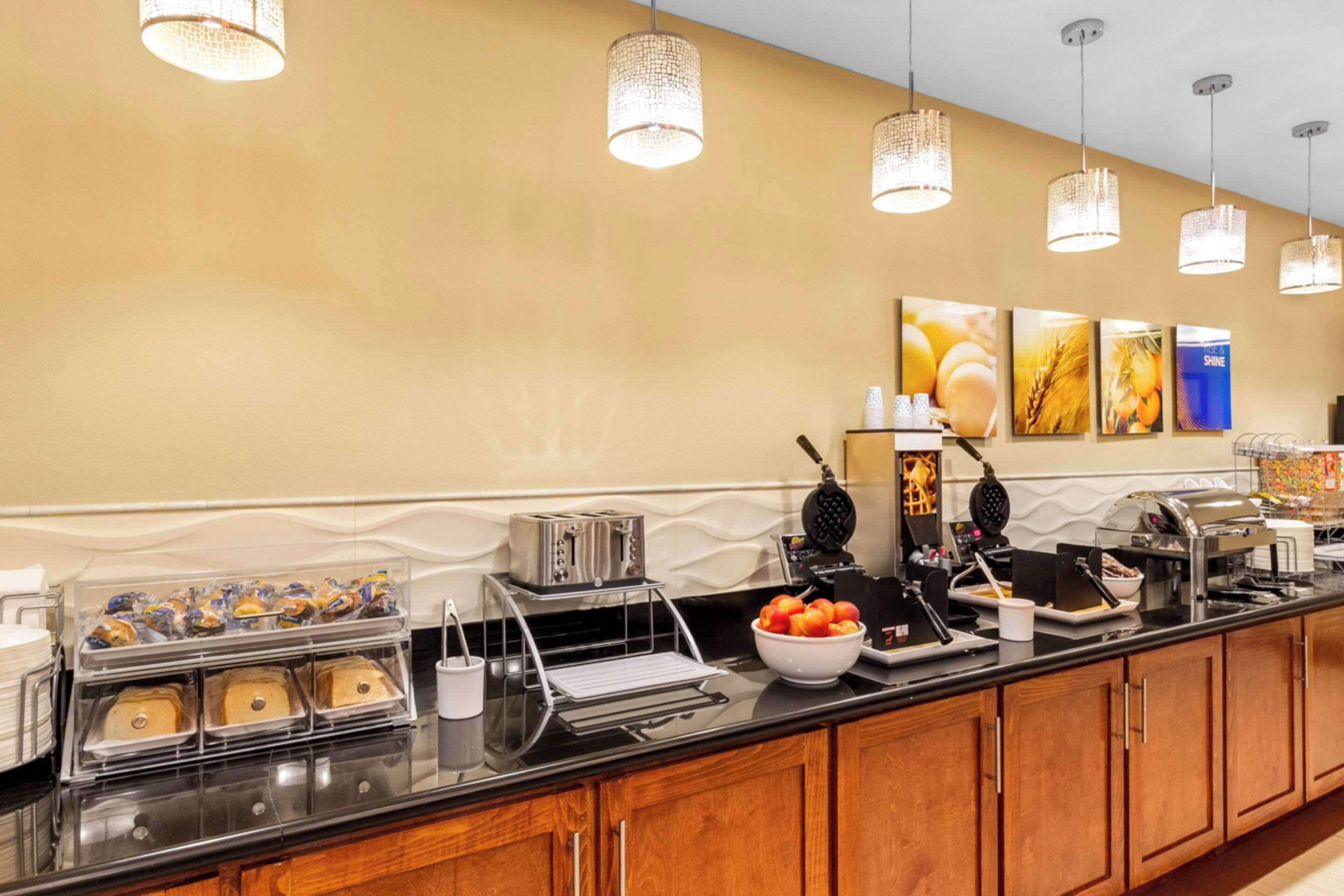 A breakfast bar with various food options, a toaster, waffle maker, and a coffee station.