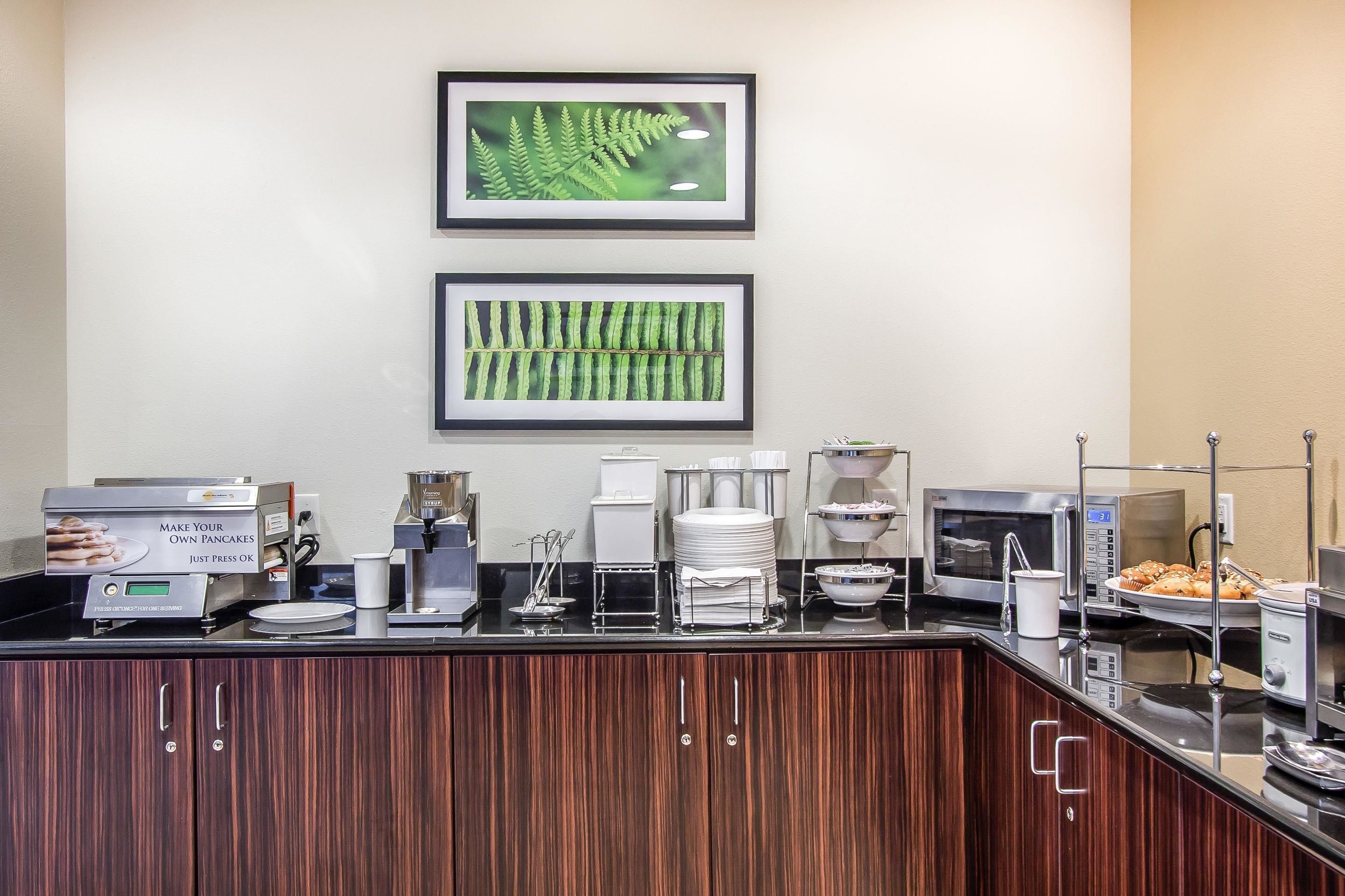 A breakfast bar with a coffee machine, a microwave, and a display of pancakes.