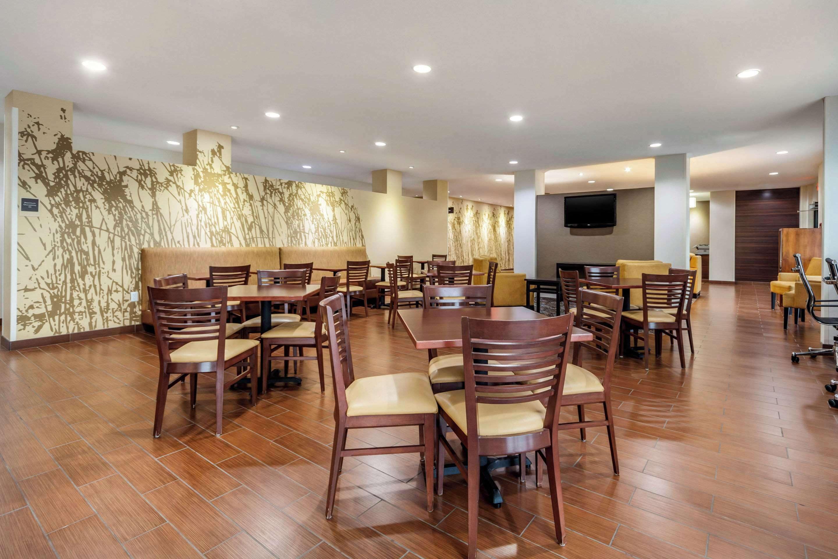 Un grand espace dédié à la salle à manger, avec plusieurs tables et chaises, un téléviseur à écran plat fixé au mur et un motif décoratif sur le mur.