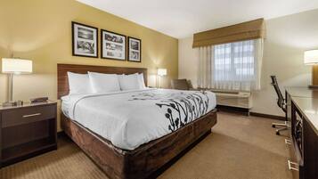 A hotel room with a large bed, bedside tables, a desk, and a window with curtains.
