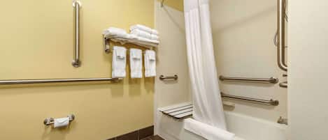 Un baño con inodoro, ducha con barras de apoyo y toallas en un perchero.