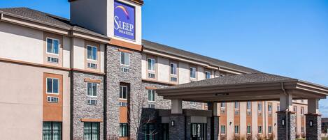 A Sleep Inn & Suites hotel with a modern design, featuring a covered entrance and multiple windows.