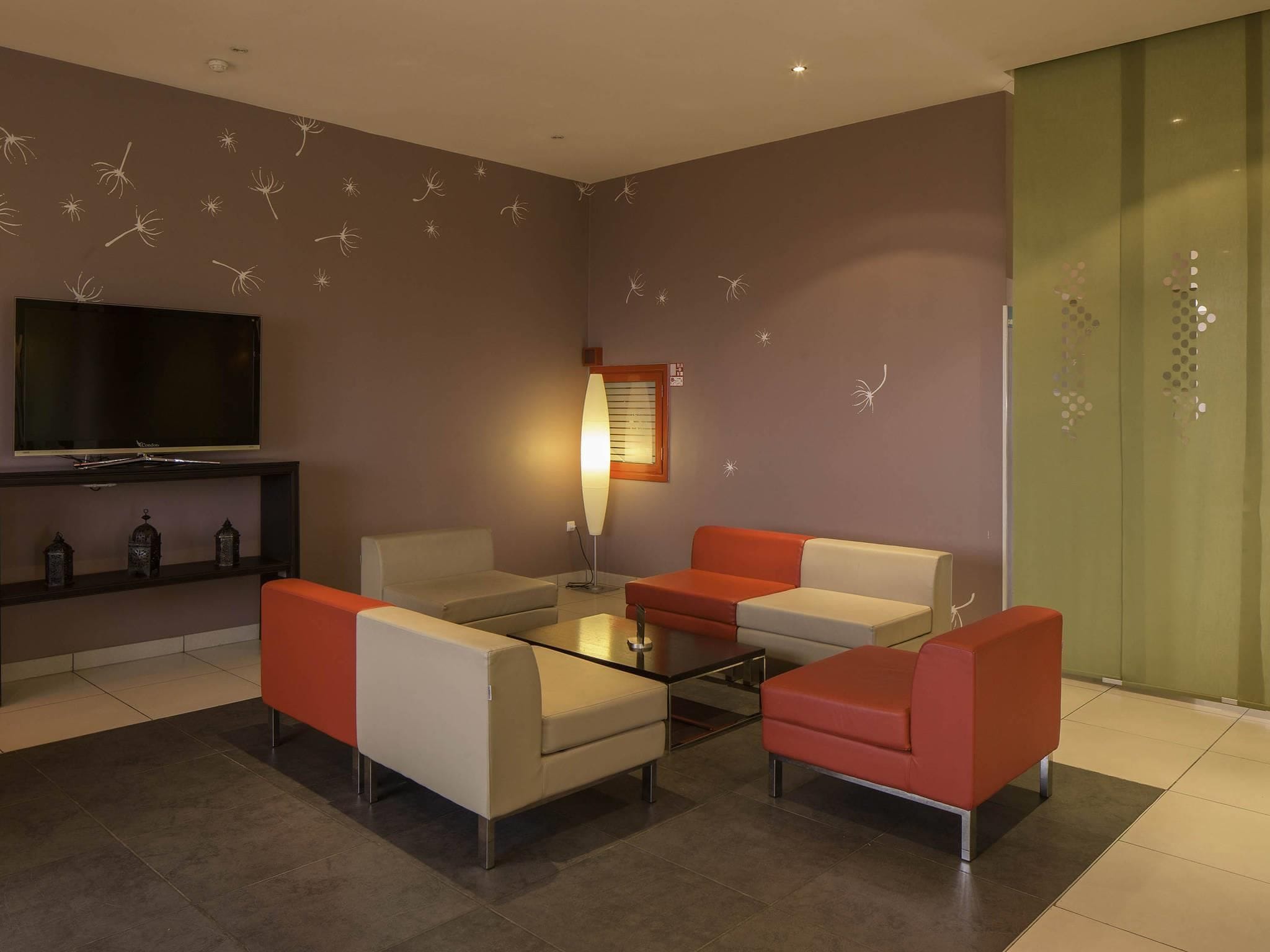 Una sala moderna con televisor de pantalla plana, dos sofás, una mesa de centro y adhesivos decorativos en la pared.