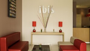 Un hall d’entrée moderne avec des canapés rouges, un comptoir d’accueil et une œuvre d’art accrochée au mur.