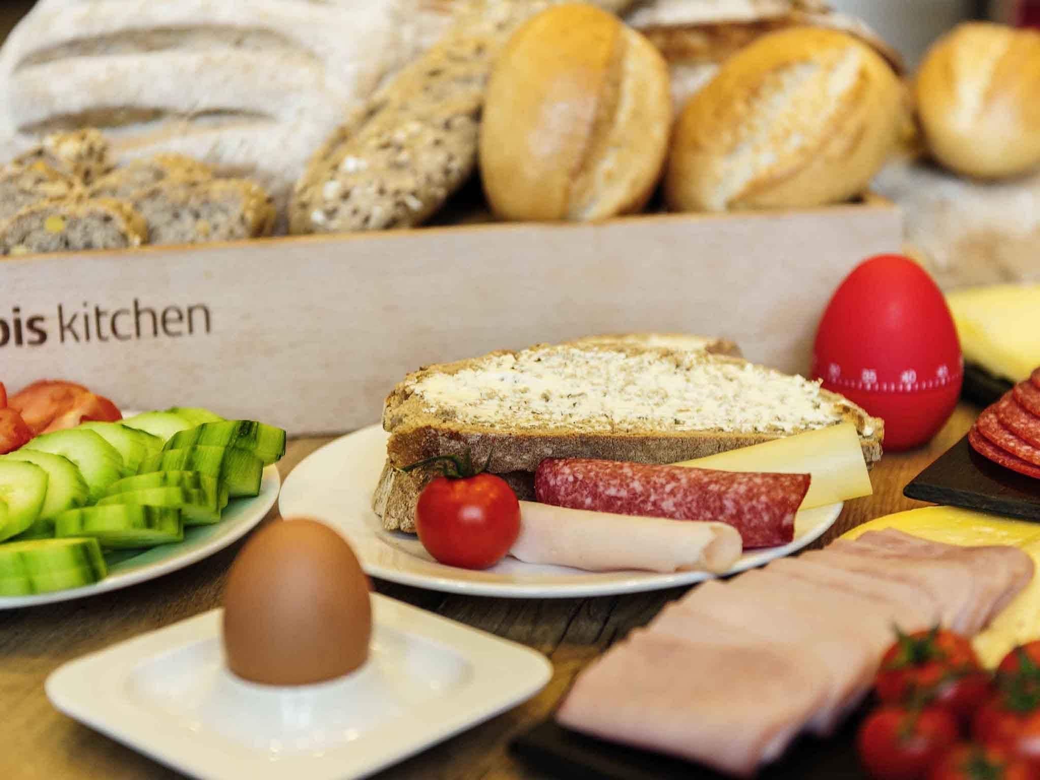 Variedad de alimentos sobre una mesa, incluyendo pan, queso, carne y verduras.