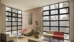 Un espace de détente moderne avec de grandes fenêtres, des sièges confortables et une plante en pot.