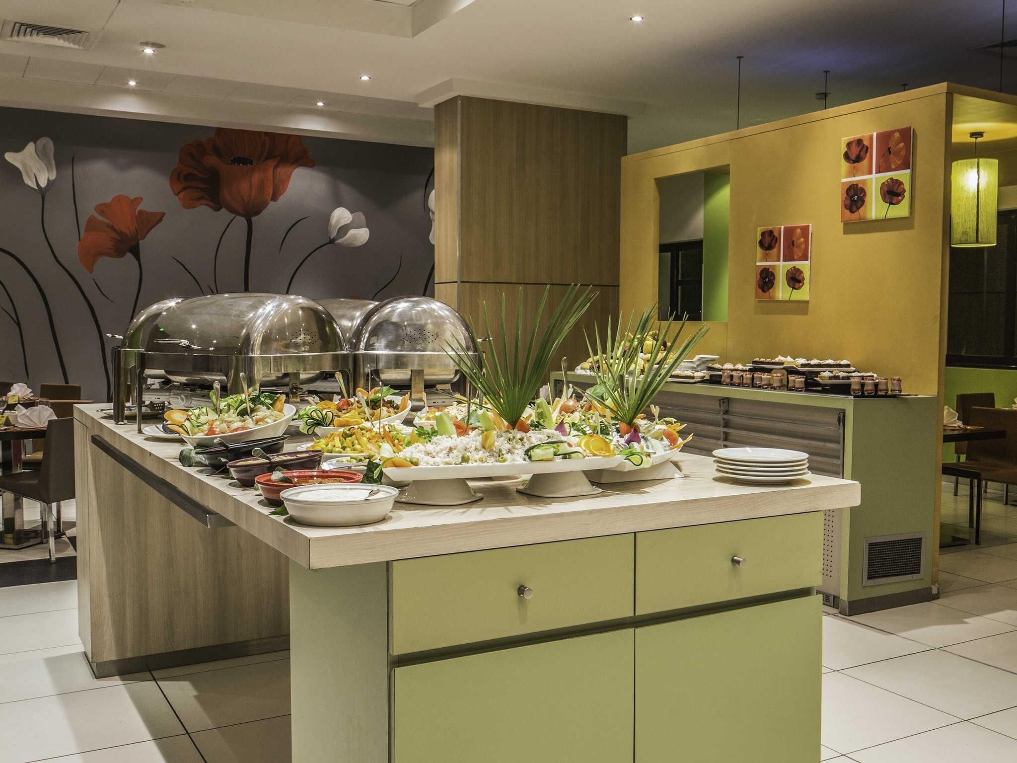 Montaje de buffet con diversas opciones de comida y una pared decorativa con motivos florales.