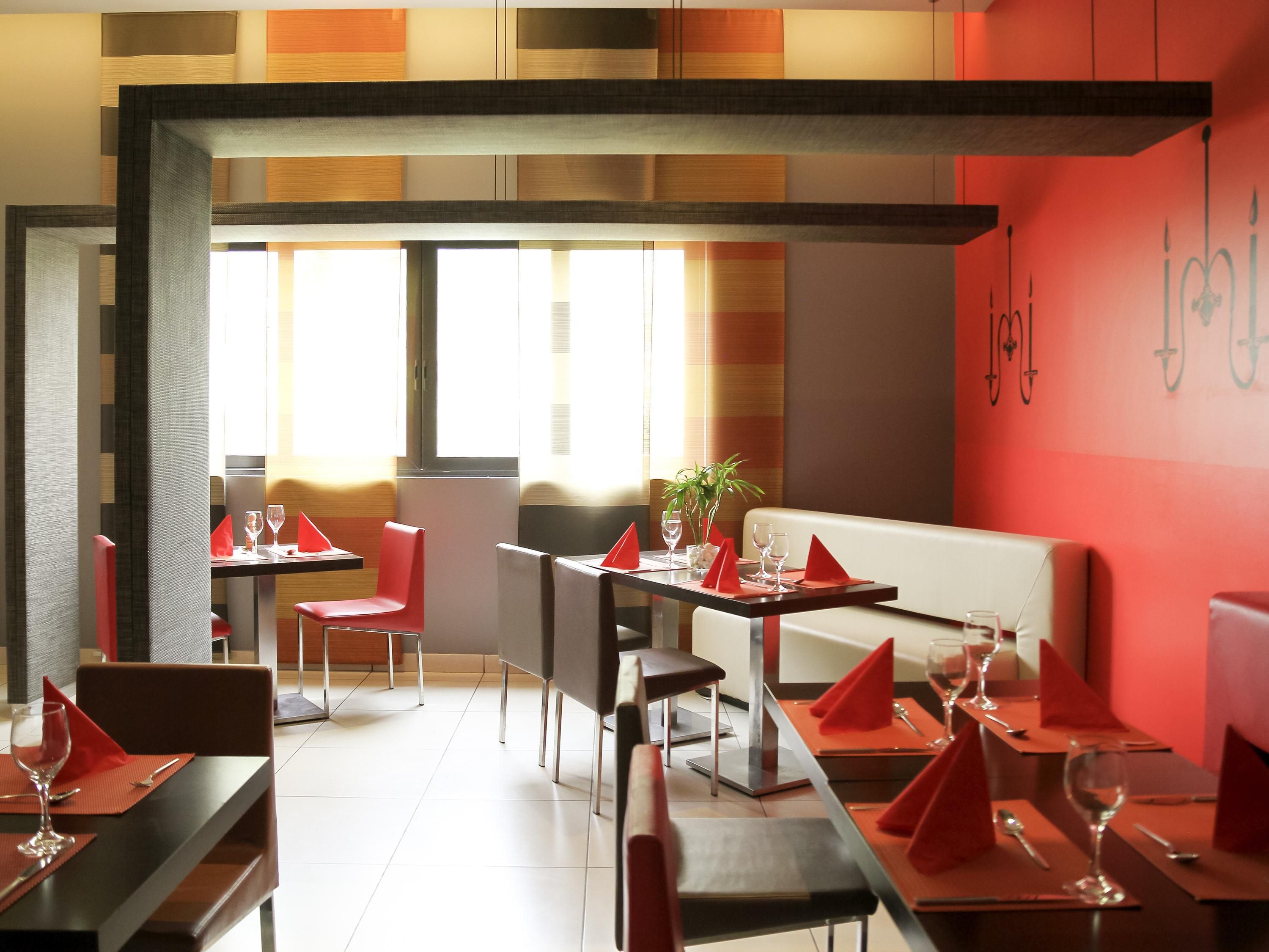 A restaurant interior with tables set for dining, chairs, and a seating area with a sofa.