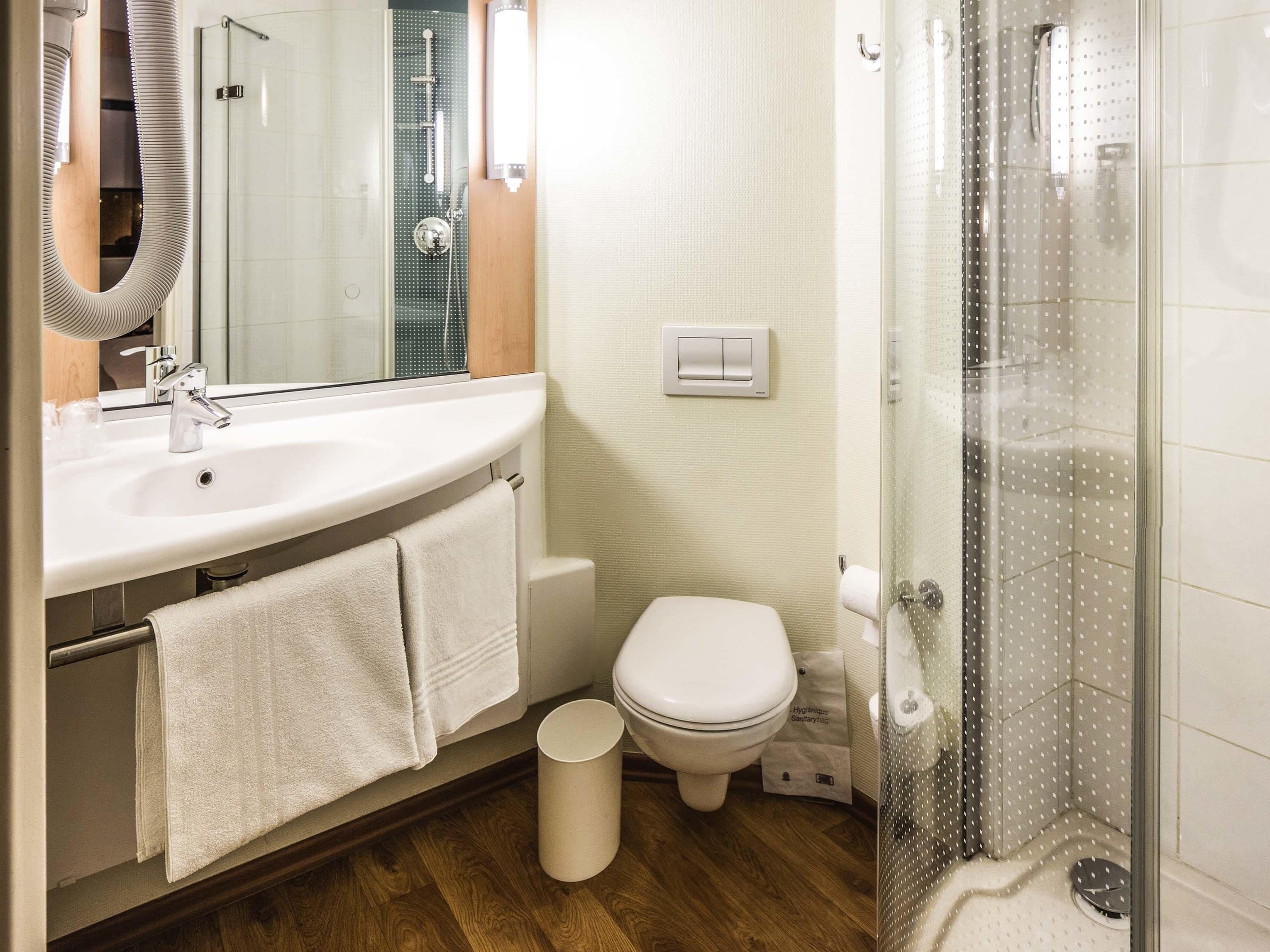 Un baño con lavabo, espejo, toallero, inodoro y cabina de ducha de vidrio.