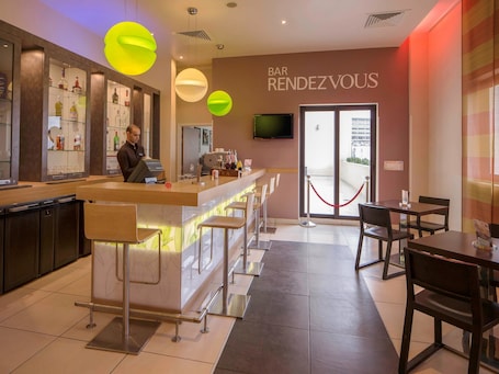 A modern bar area with a bar counter, stools, and a television screen.
