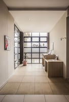 Una zona de recepción moderna con puerta de cristal, mostrador y una planta en maceta.
