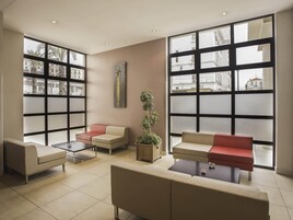 Un área de descanso moderna con ventanas amplias, asientos cómodos y una planta en maceta.