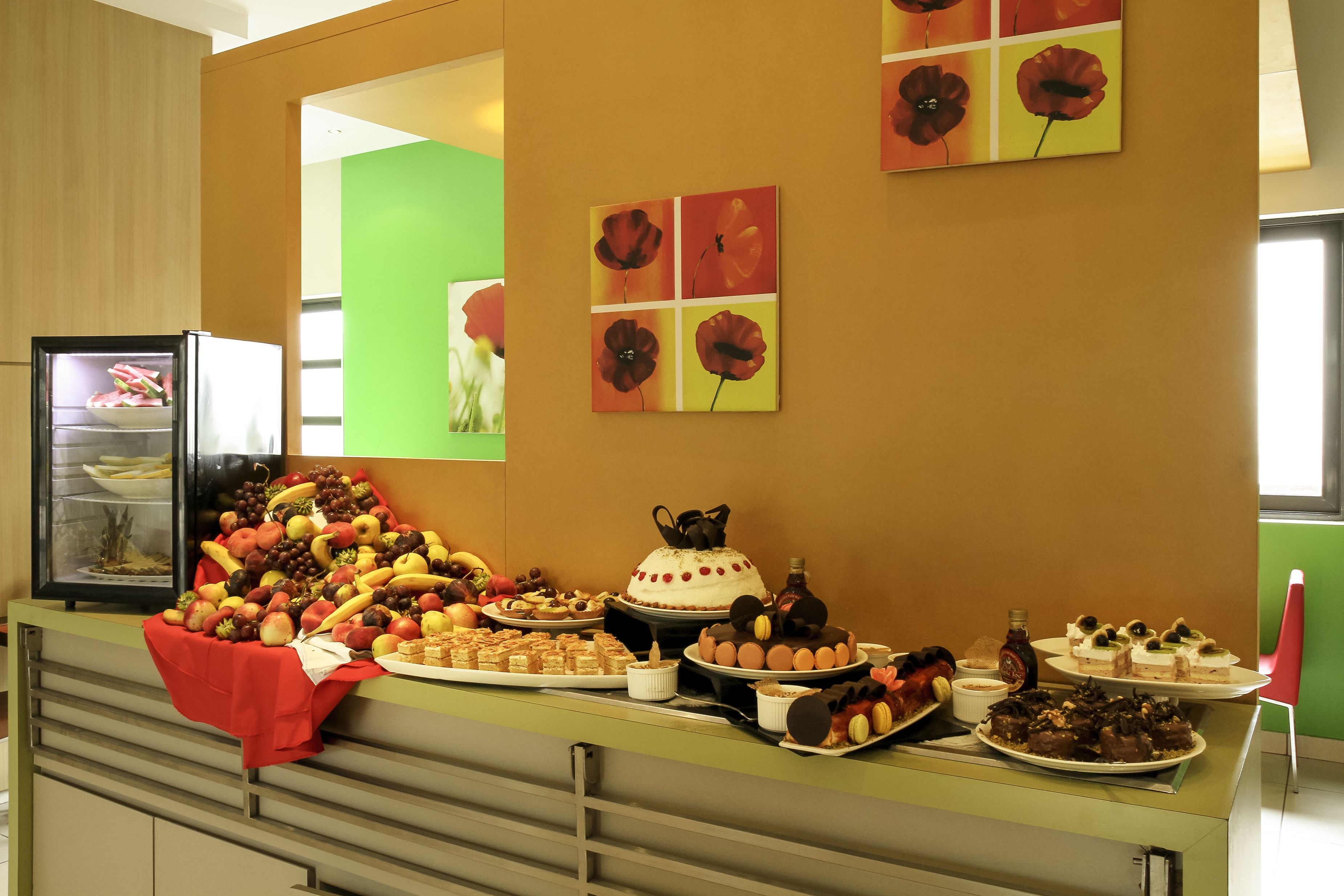A buffet table with various food items and a refrigerator.