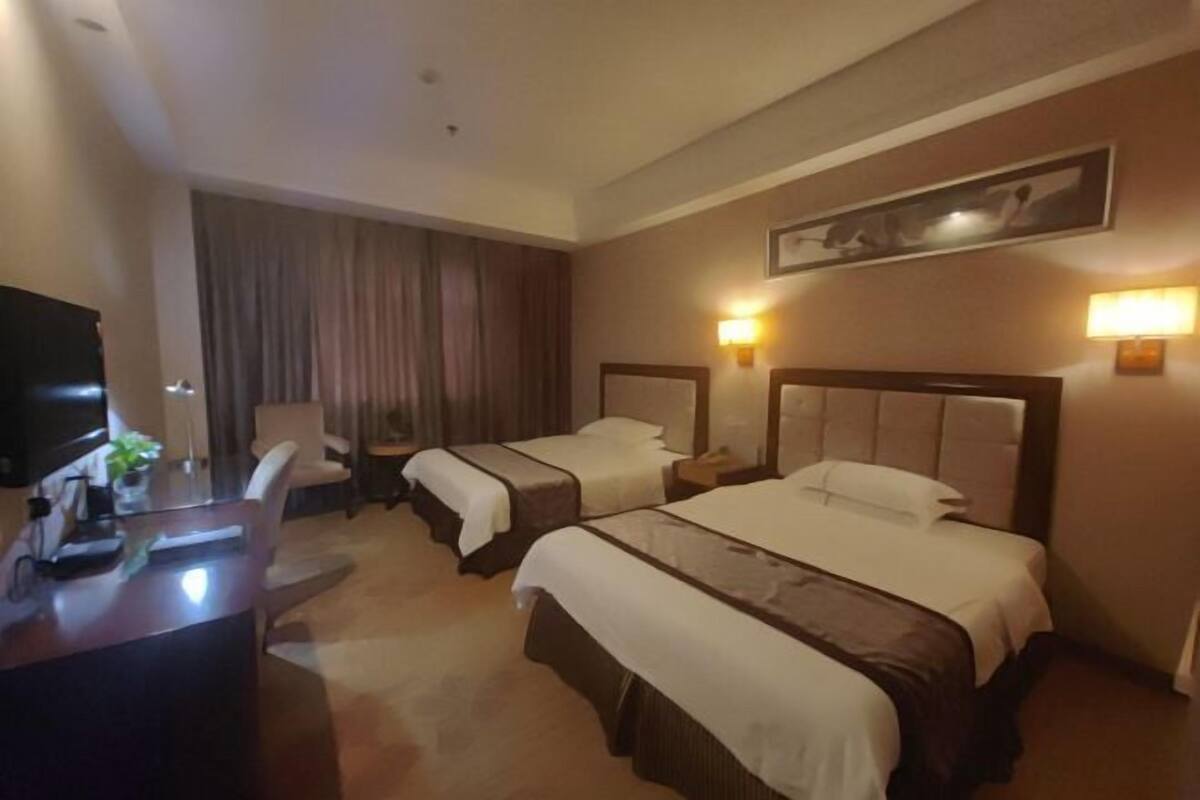Een hotelkamer met twee bedden, een bureau, een stoel en een televisie.