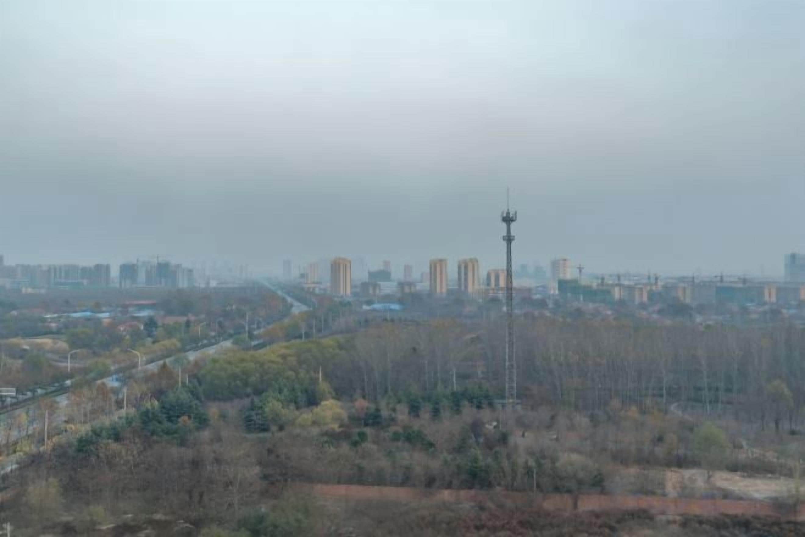 A cityscape with a prominent communication tower, residential buildings, and a road.