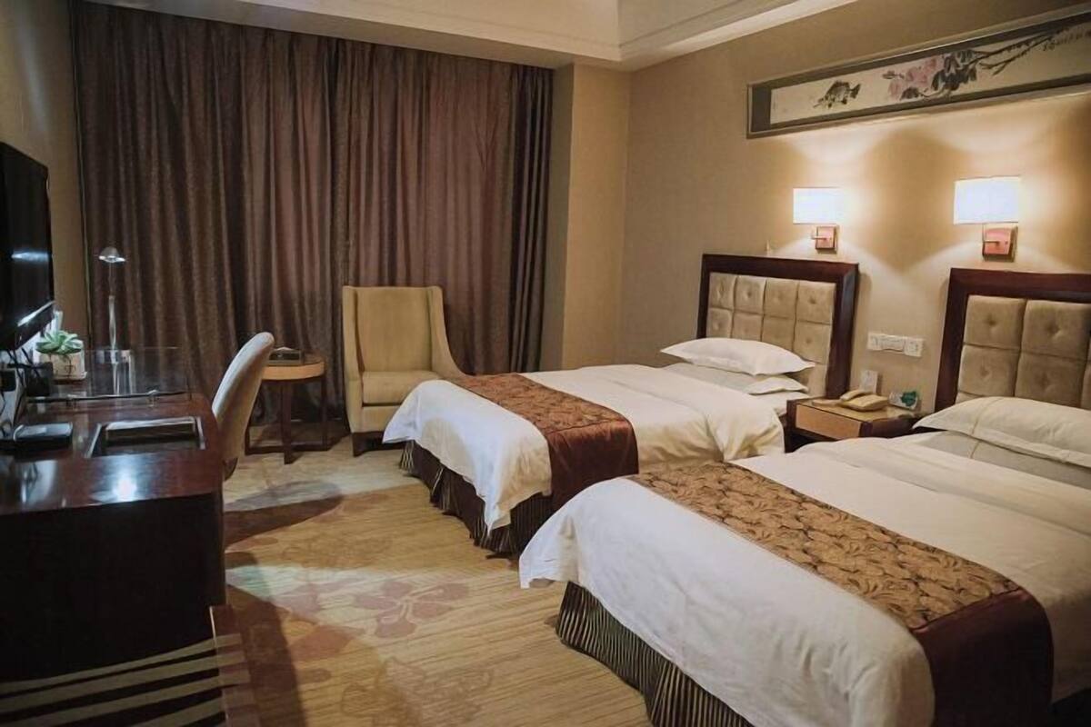 Een hotelkamer met twee bedden, een bureau, een stoel en een televisie.