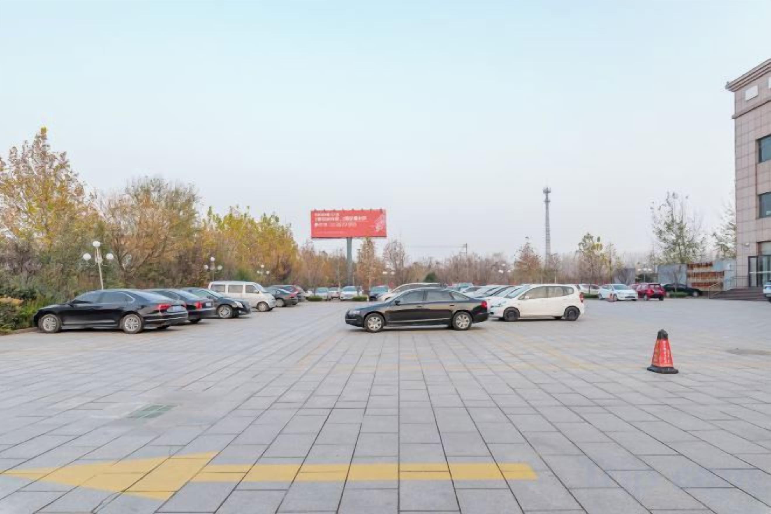 Un parking avec plusieurs voitures et un bâtiment en arrière-plan.