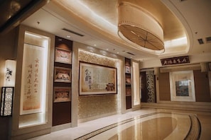 A spacious lobby with a large central display, decorative wall panels, and a polished floor.